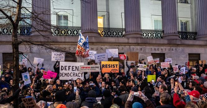 A group of protesters holding signs outside the Department of the Treasury.
