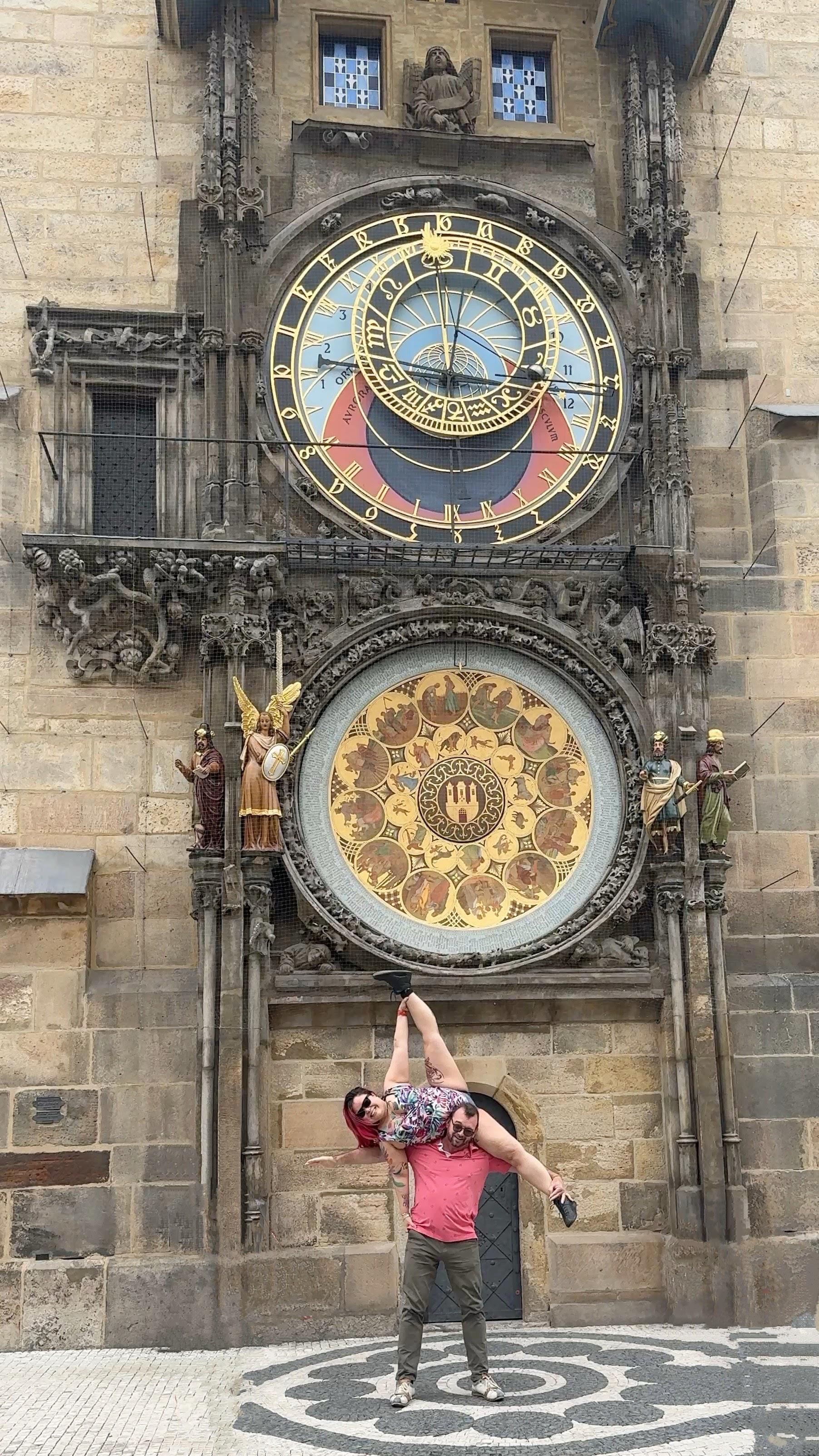 Nicole and her partner doing an acro pose in front of the astronomical clock in Prague, Czech Republic