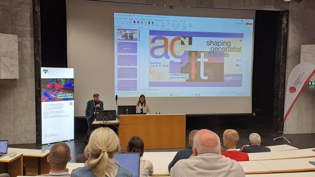 Speaker and moderator in front of screen