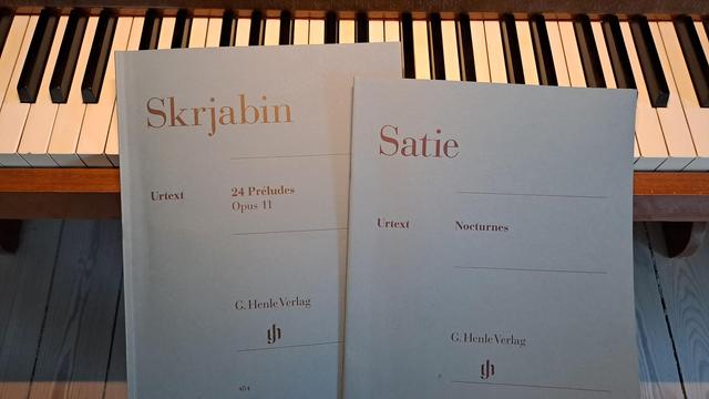 Photo of two Urtext versions of Skrjabin's Preludes (Op 11) and Satie's Nocturnes, on top of piano keys