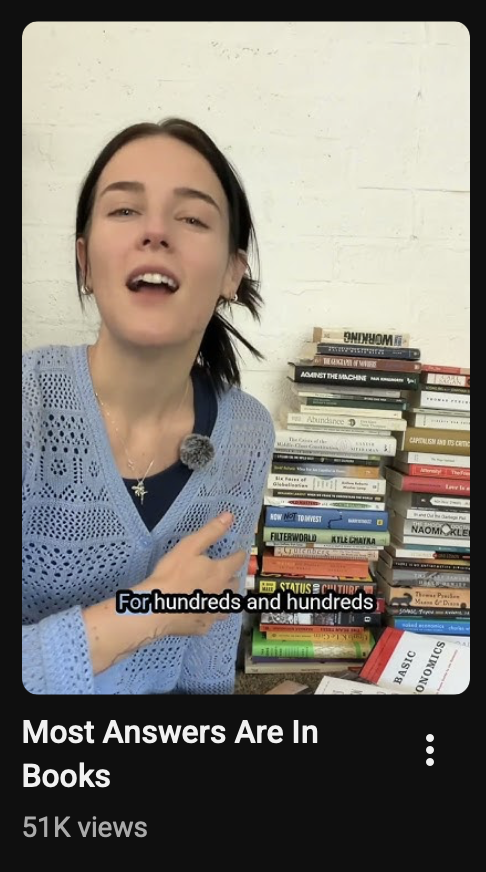 A thumbnail of a YouTube short video with the title "Most Answers Are In Books". An excited-looking young woman sits next to a pile of books, presumably eager to share her discovery.