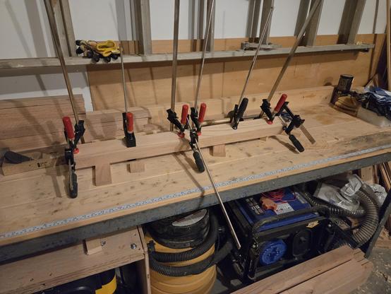 leg five sitting on the workbench being glued with lots of clamps.