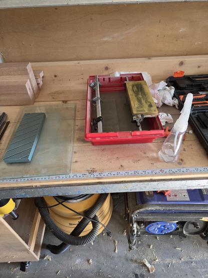my sharpening setup sitting on my workbench.  there is a water basin with a stone on top, a squirt bottle of water, and my flattening stone.