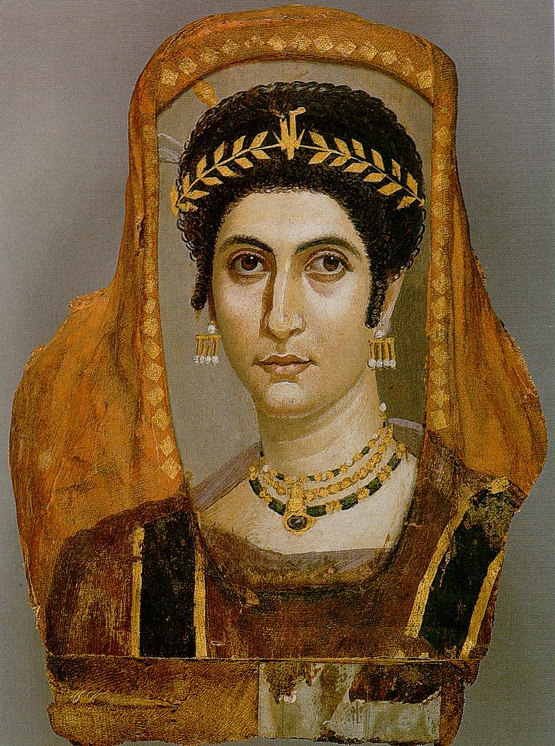 A crown of justification on a death image of a dead woman named Isidora from the early Roman period. These were placed on the coffins of the dead during that period, but the crown of justification is first described in the Book of the Dead, over 1500 years before the Roman period. The woman here is a pale woman with black cury hair wearing a red dress with jewels, and a laurel crown on her head.