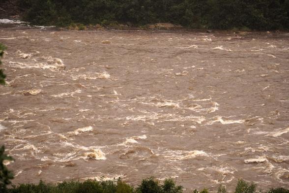 The Mōkihinui River is high and full of whitecaps in the rain.