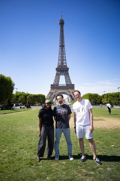 Trois personnes qui sont debout avant le Tour Eiffel, une femme et deux hommes.