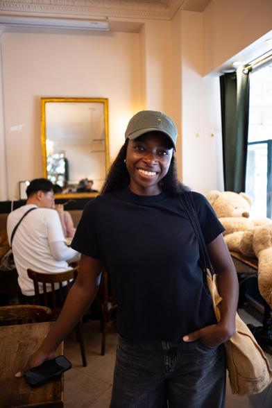 Une femme qui pose pour la caméra, étant debout, avec une sourire.