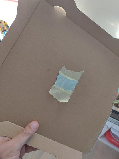A piece of cardboard with a tiny piece of tinfoil that has a pin prick hole