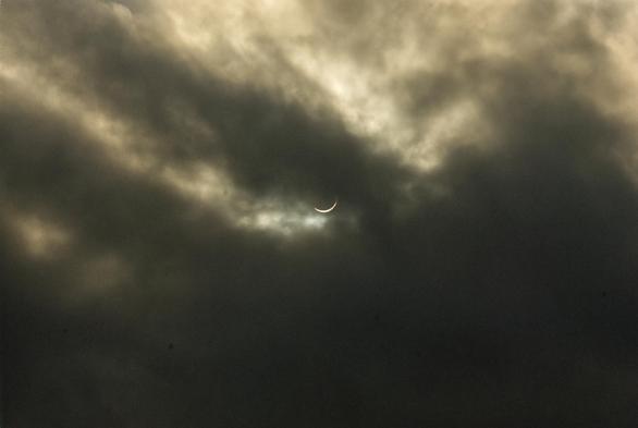 solar eclipse in poking through the clouds.
the eclipse is in the middle just under this dark cloud finger