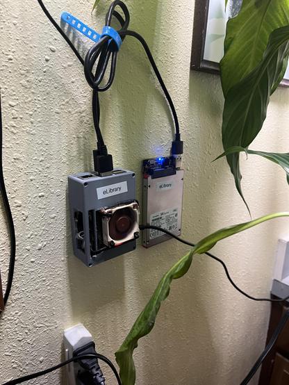 a picture of a raspberry pi 4 and a usb connected sata drive stuck to a wall.