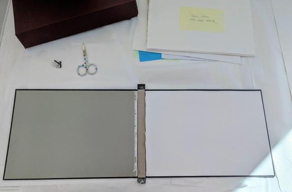 Open deconstructed case binding (book cover) showing endleaves, spine reinforcement, pages of a partial textblock section. Small scissors sit near the case as well as the textblock with a post it note.

*please note, do not use post it notes on documents. They are a future preservation issue.