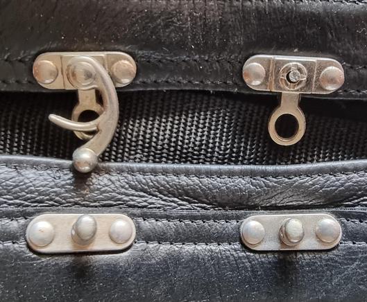 Silver rotating riveted closure for leather.
