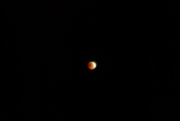 lunar eclipse at maximum.
the moon is in the center.
it is mostly a copper coloured ball with a small yellow-white crescent on the right.
