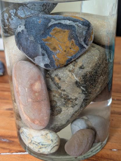 Various colorful large rounded pebbles sit together in a simple glass vase, showing off their contrasts thanks to the water.

The blue and yellow one at the top is my favorite.

Staring into the light blue veins between the dark blue and yellow islands I imagine the millions of years this one has traveled and marvel at how this product of geology looks like a map of an ancient world