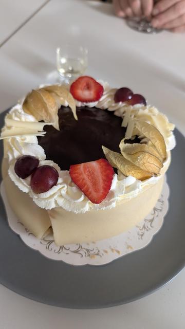 Picture of a cake with fruit on top, whipped cream with marzipan all the way around