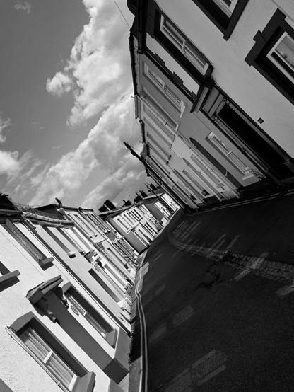 A small quaint village street of terrace houses, black and white photo. The photo is rotated 45 degrees for a different composition