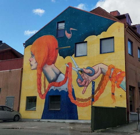 Large, newly painted wall och a hand with scissors cutting of a very long orange braid of a long-necked person.