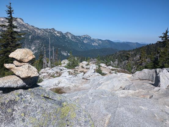 A cairn is stacked on a boulder to the left. Before us is a slope of undulating granite.