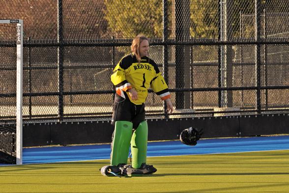 A field hockey goalie doffing his helmet before the game.