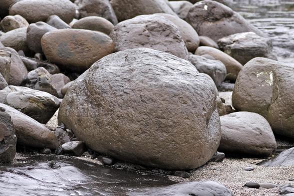 A small rounded boulder. Well, small is relative. I wouldn't want to pick this up. It looks like a potato. There are smaller rocks around it.
