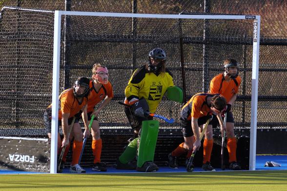 Apparently this is a penalty corner. The goalie plus four other players are in the net, and the players run out at the start of play.