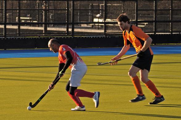 The same player from before is also running with the ball. This time there is an orange shirted opponent who is looking on.