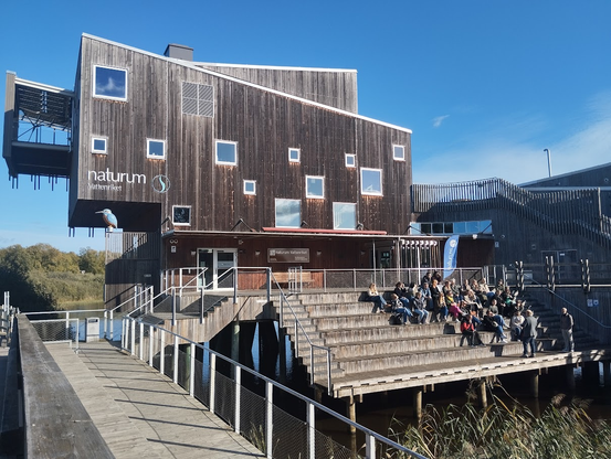 Pretty cool building with wooden panels and a kind of outside lecture place with seated people in front of a lecturer who was interesting.