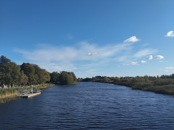 Large, calm body of water beneath a blue sky with a few fluffy clouds.