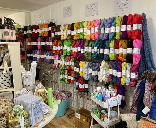 A yarn shop with a wall of brightly coloured hanks of yarn.
