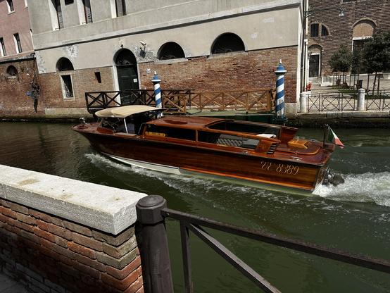 A wooden (most likely mahogany) taxi boat in a river of venice