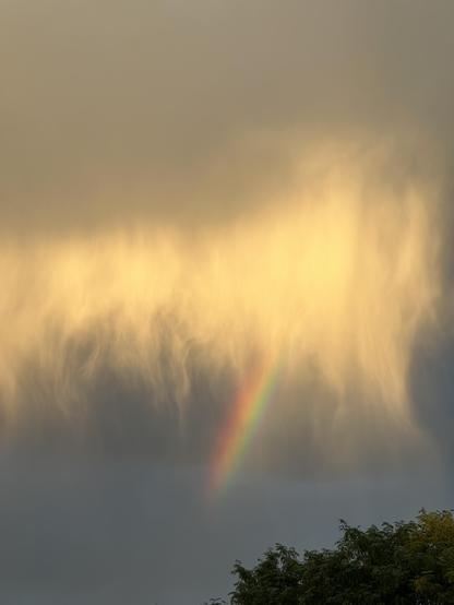 Virga, it’s raining but the air at ground level is so dry it doesn’t each the ground. Sunlight filters thru the clouds to show threads of rain with a stub of a rainbow in the center. September 2026