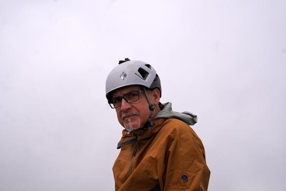 A person wearing a helmet looks at a camera. Not much to look at behind: it's just mostly white.