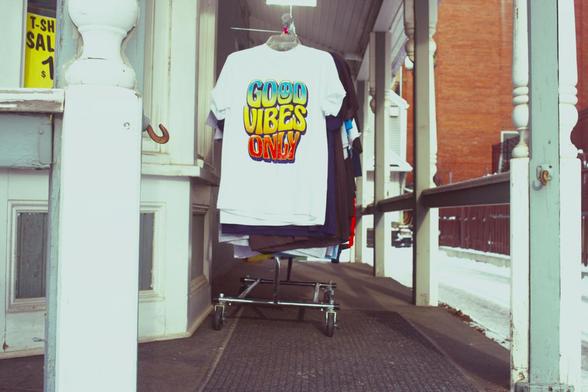 T shirt that says "good vibes only" hangs on a patio in winter.