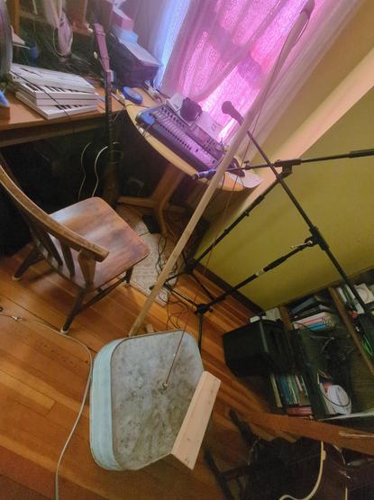 Wide angle shot showing a washed up base on the floor, its stick leaning against a couple of microphone stands, a desk with some kind of digital mixing board in the background.