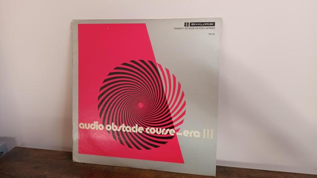 Album cover - audio obstacle course. An abstract swirling circle image on a slashed red background