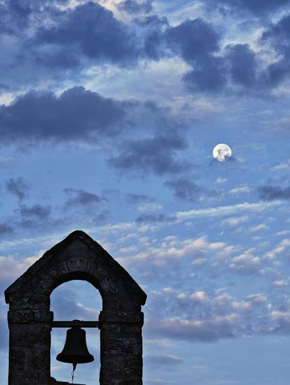 Ein nächtlicher Himmel mit Mond. Im Vordergrund ein Glockenturm.