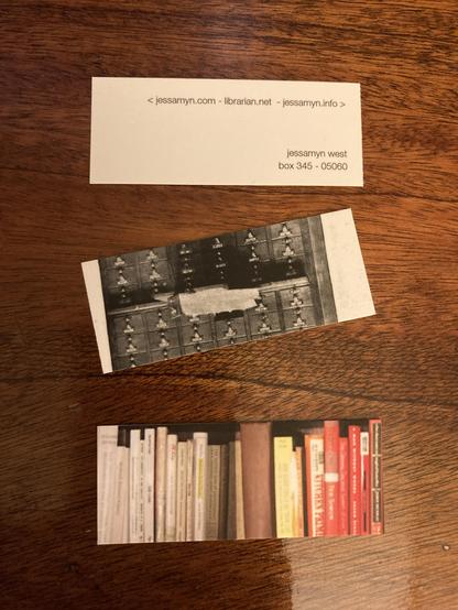 Two Moo cards which are like lengthwise narrower business cards, one has a black and white partial image of a card catalog and one has a bookshelf with the books arranged by color. The last is showing the reverse which has my three websites as well as my postal address.