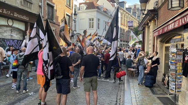 A large group of people in the street for Bear Pride March near Mannekin Pis. Many carry flags.
