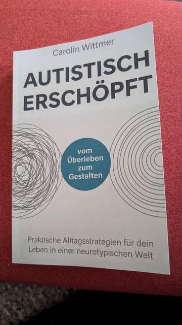 Buchcover in weiß, darauf steht: Carolin Wittmer, Autistisch erschöpft. Vom Überleben zum Gestalten. Praktische Alltagsstrategien für dein Leben in einer neurotypischen Welt.