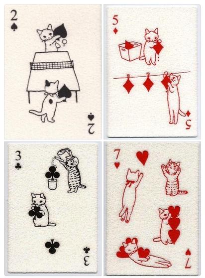2 of Spades: Two cats playing ping-pong using the spade pips as paddles.

5 of Diamonds: One cat taking diamonds out of a box while another hangs them up on a clothesline.

3 of Clubs: One tabby cat watering a potted club pip like a plant, while another carries a cluster of clubs.

7 of Hearts: Multiple cats stretching, playing, and lounging with a collection of floating red hearts.