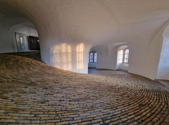 Inside of a tower in Copenhagen, a paved road wide enough for horse and carriage. White walls and a round pillar in the center (which is actually hollow and you can look down in it).