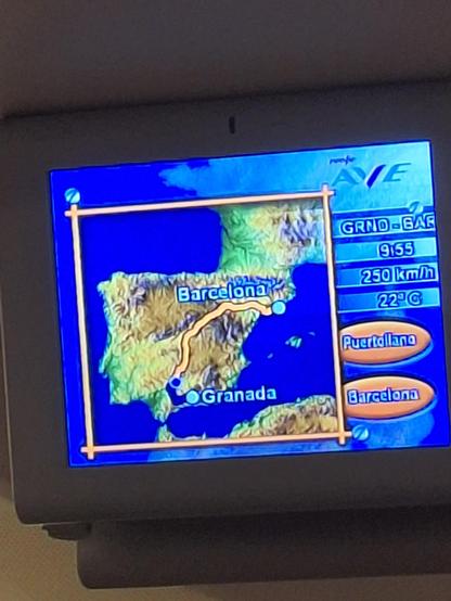 Fotografía de una de las televisiones del tren. Se ve un mapa de España con el recorrido que hace el tren de Granada a Barcelona. La línea va primero hacia el suroeste, a Antequera, luego al norte a Córdoba, luego a Madrid, luego a Zaragoza, y finalmente llega a Barcelona.
La pantalla marca algún dato más: son las 09:55, el tren va a 250 km/h, hay 22 grados, y la próxima parada es Puertollano.