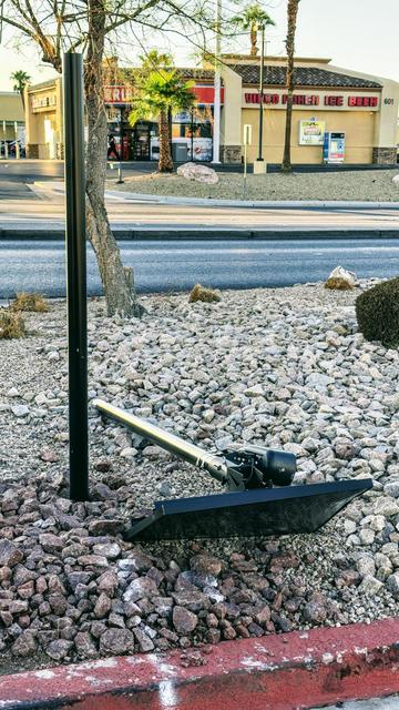 A flock camera seen laying on the ground, apparently removed from its mounting pole and left laying there