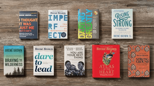 Eight Brené Brown books are arranged in two rows on a wooden surface, including I Thought It Was Just Me (but it isn’t), The Gifts of Imperfection, Daring Greatly, Rising Strong, Braving the Wilderness, Dare to Lead, You Are Your Best Thing, Atlas of the Heart, and Strong Ground.