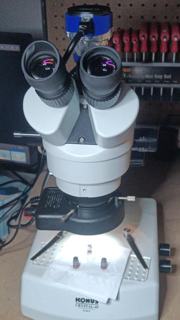A trinocular microscope (a binocular microscope with camera port) on a workbench.