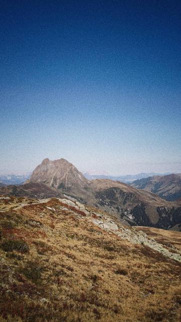 A hiking trail heading into distance. A single mountain in front of a distant sky.
