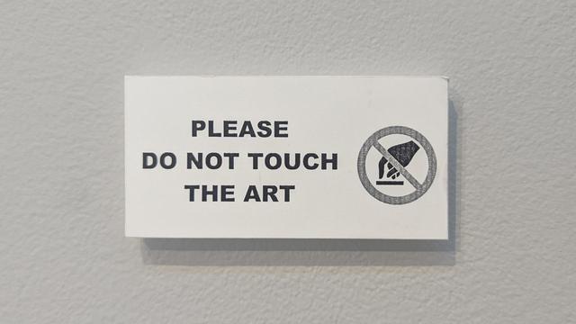 a sign next to the wall of art cushions instructs the public "please do not touch the art"