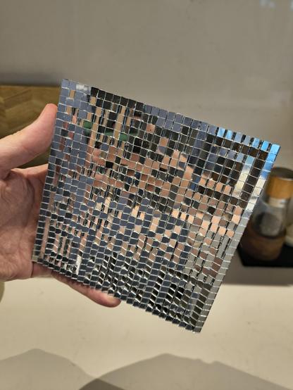 square grid, about 6 inches by 6 inches, covered in 5 millimeter mirror tiles tilted at different directions.
