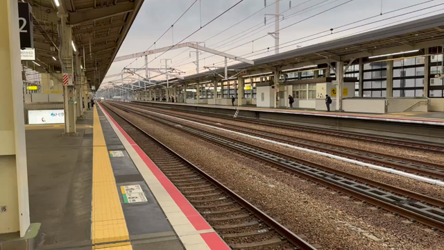 21s video. View of a train station with two platforms and their tracks and two extra tracks between them for trains to pass that do not stop at that station. A Japanese Shinkansen Nozomi Superexpress passes at ~300km/h on one of the inner tracks. The camera swings around as the end of the train passes.