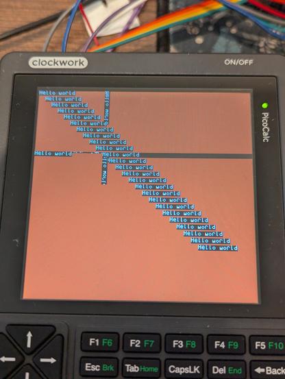 A PicoCalc with the display showing repeated glitchy Hello World text in a rather small font